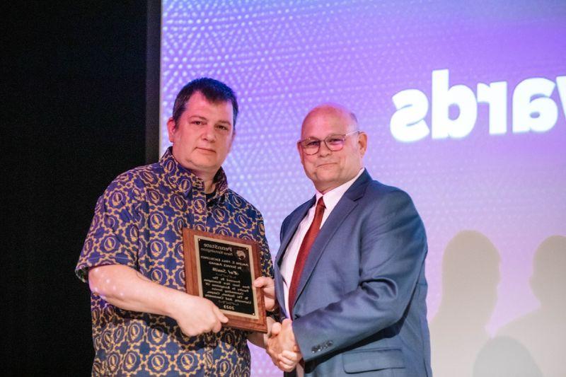 Two individuals standing and holding plaque